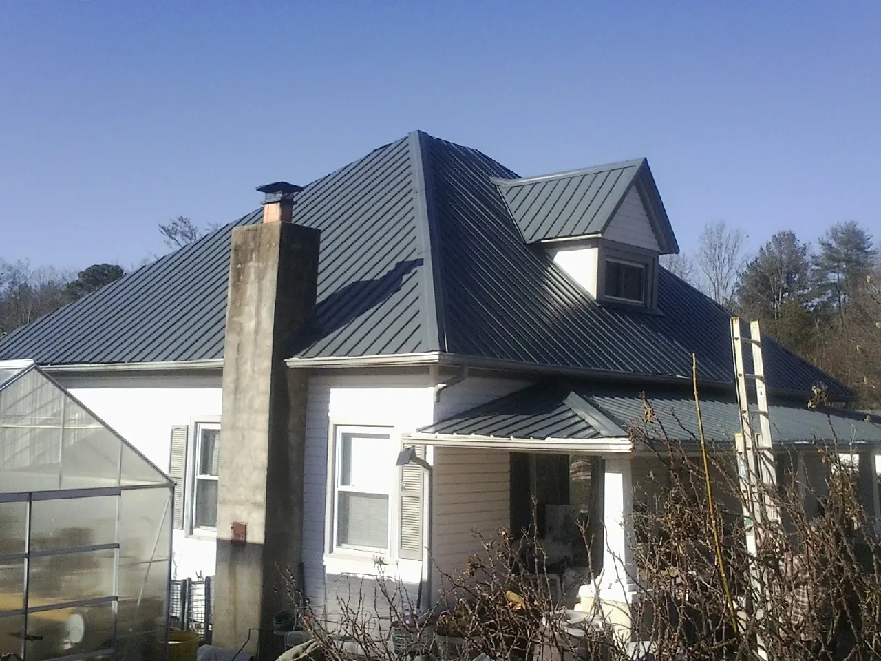 Dark blue standing seam metal roof on a white farmhouse with dormer — Slate & Tile Roof Repair by Roofing Brothers in Kearneysville