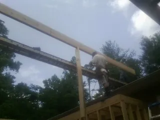 Carpenter setting a ridge beam over a new addition frame — Ice Dam Removal by Roofing Brothers in Kearneysville