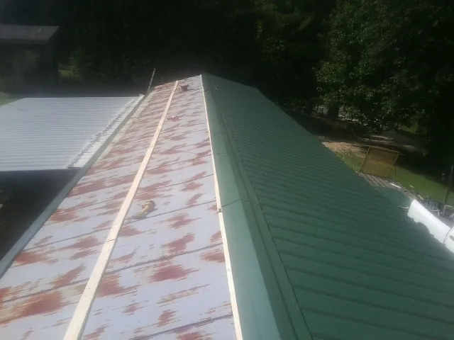 Old rusted panels beside newly installed green metal roofing — Wind Damage Roof Repair by Roofing Brothers in Kearneysville