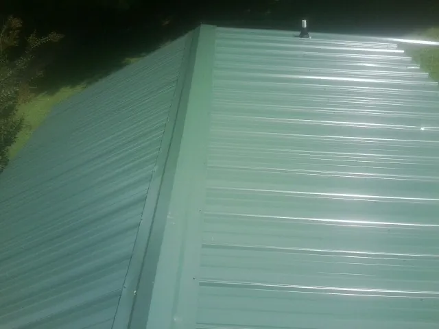 New green metal panels meeting at the ridge of a roof — Flat Roof Repair work by our crew in Kearneysville