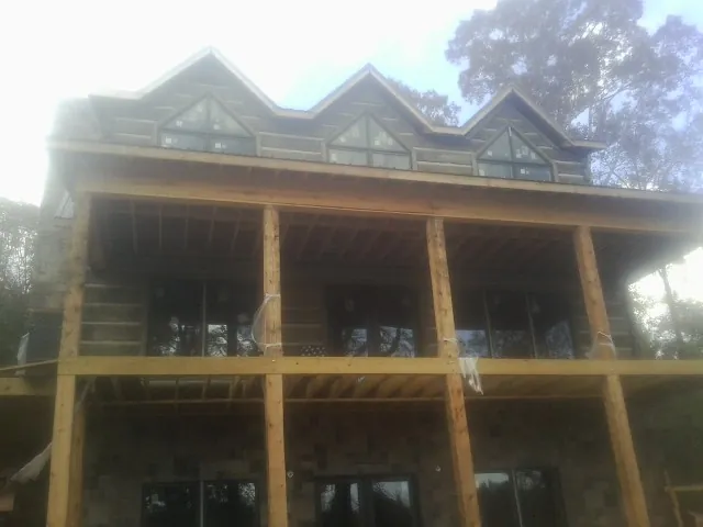 Dormers and porch framing on a large log home under construction — Roof Coating work by our crew in Kearneysville