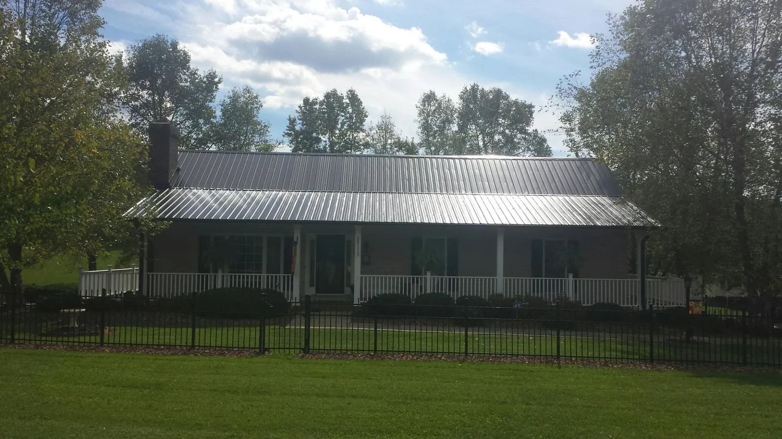 Gray metal roof on a brick ranch with a full width front porch — Gutter Guard Installation work by our crew in Kearneysville