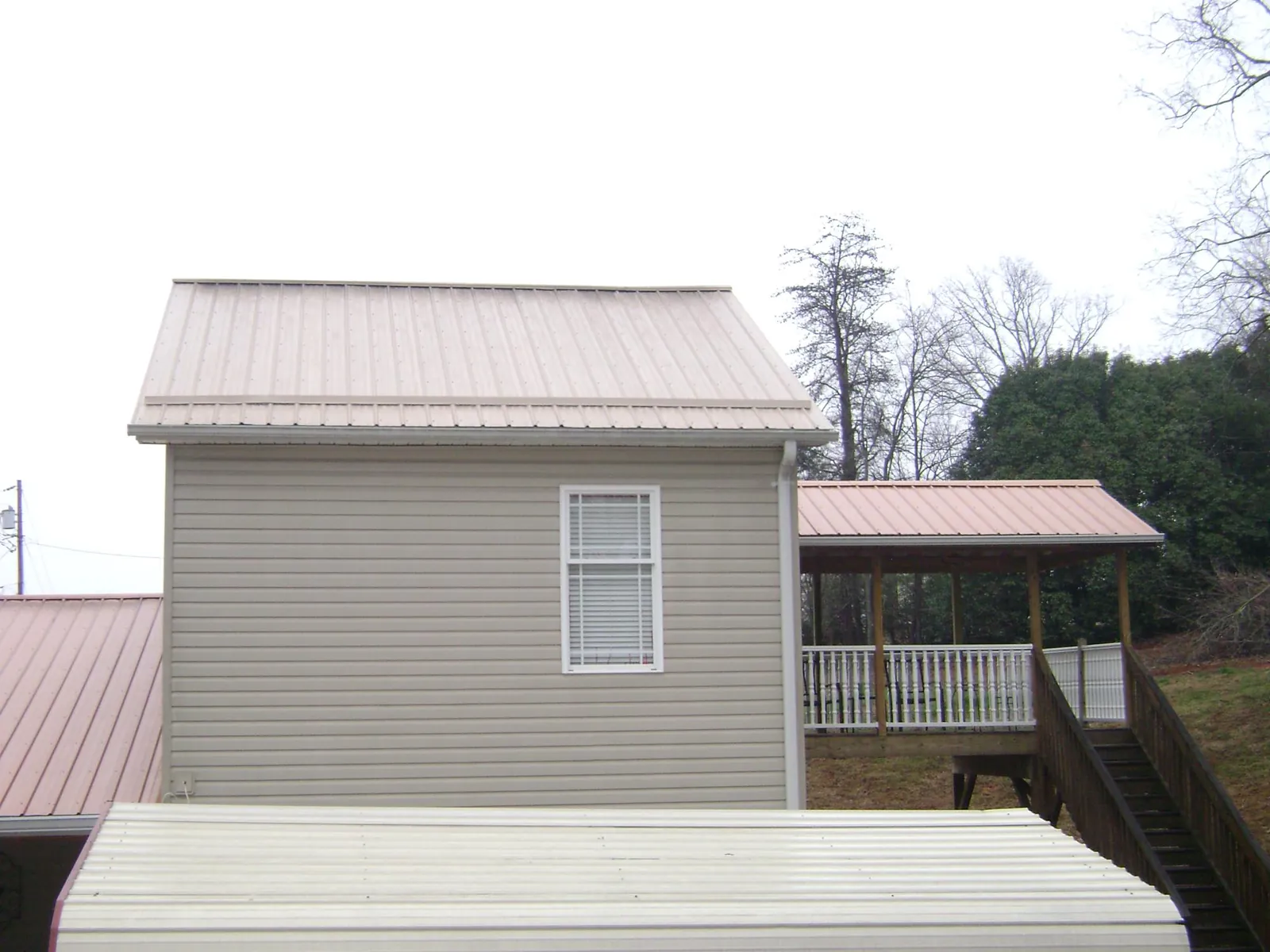 Tan metal roofs on a two story addition and attached porch, from a Roof Replacement job in Kearneysville