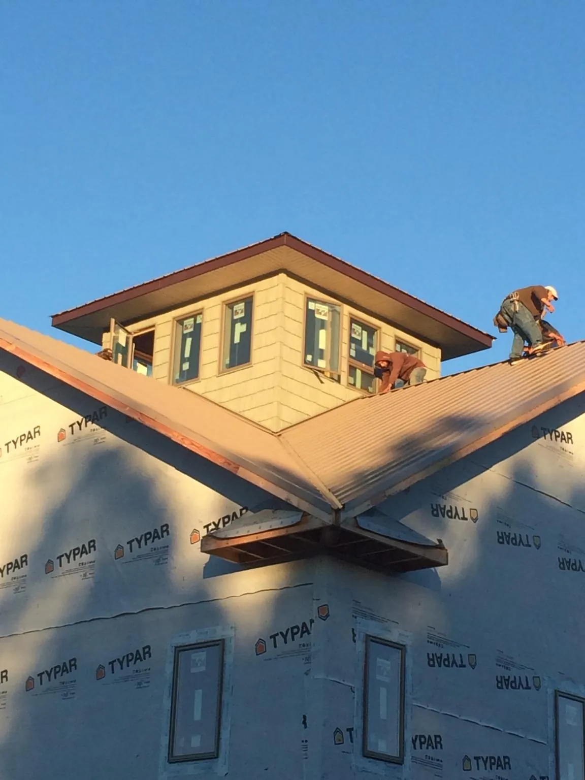 Roofers working around a rooftop cupola on a new metal roof at sunset — Roof Waterproofing in Kearneysville by Roofing Brothers